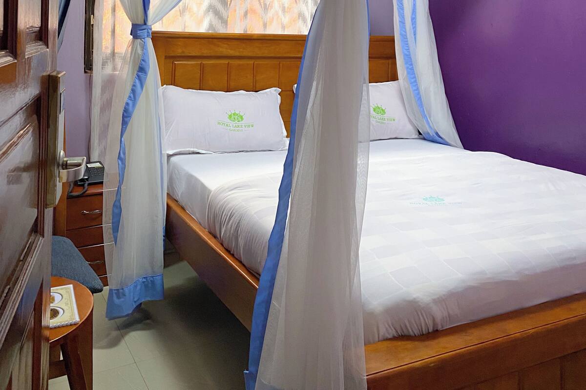 A room with a bed under a canopy, a wooden headboard, and a purple wall.