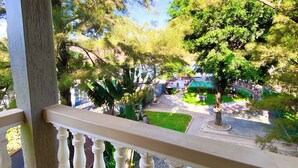 A balcony with a view of a garden, a paved area, and a parked car. - Royal Lake View Gardens (Kampala)