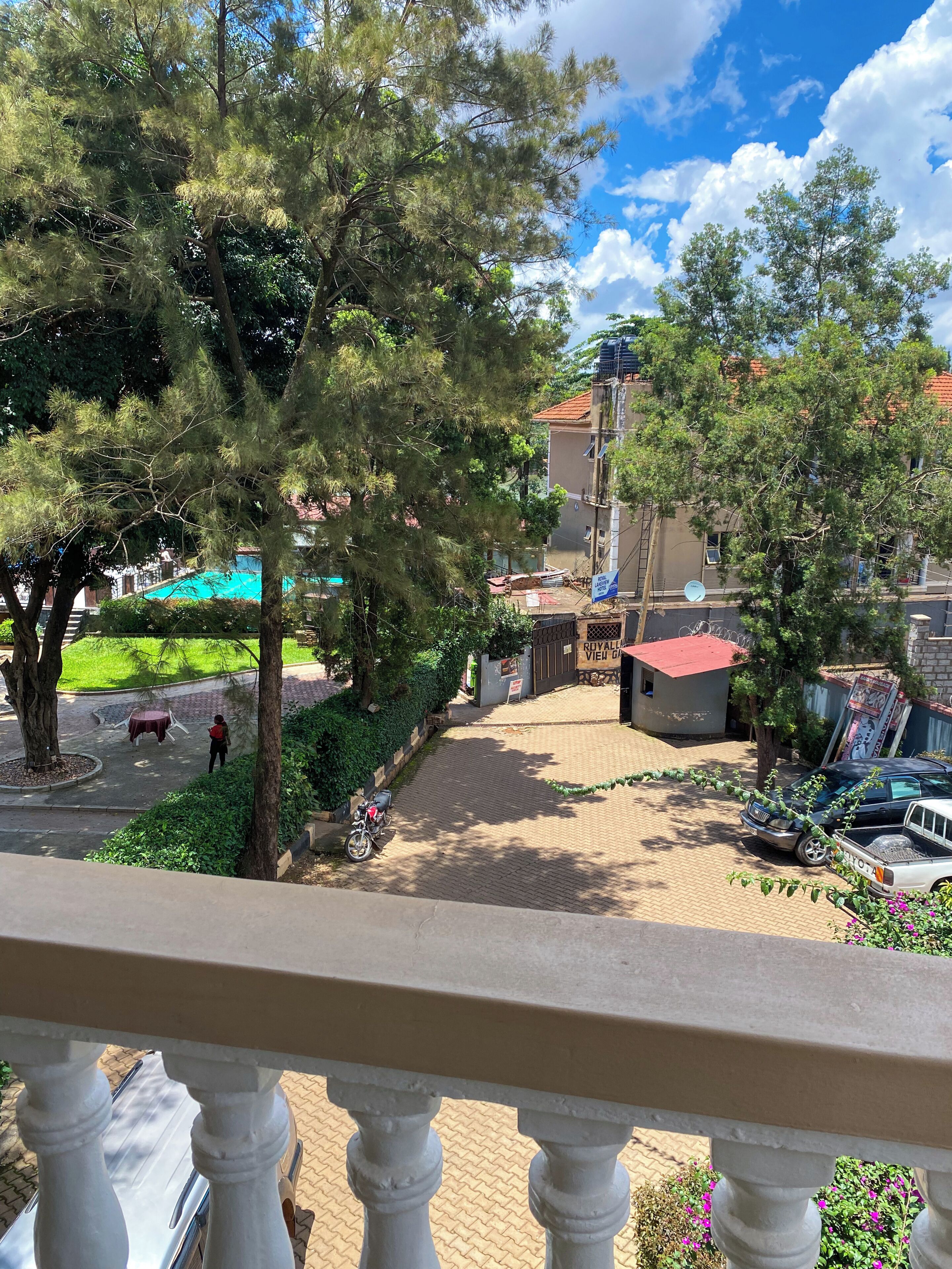 Ein Balkon mit Blick auf einen Innenhof, ein Gebäude mit rotem Dach und ein Schild mit der Aufschrift 'ROYAL VIEW'.