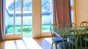 A dining area with a table and chairs, large windows, and a view of a mountainous landscape. - Queen of the Lake (Riva del Garda)