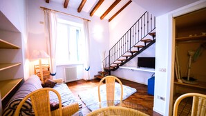 A cozy living room with a sofa, chairs, a glass table, a staircase, and a TV. - Queen of the Lake (Riva del Garda)