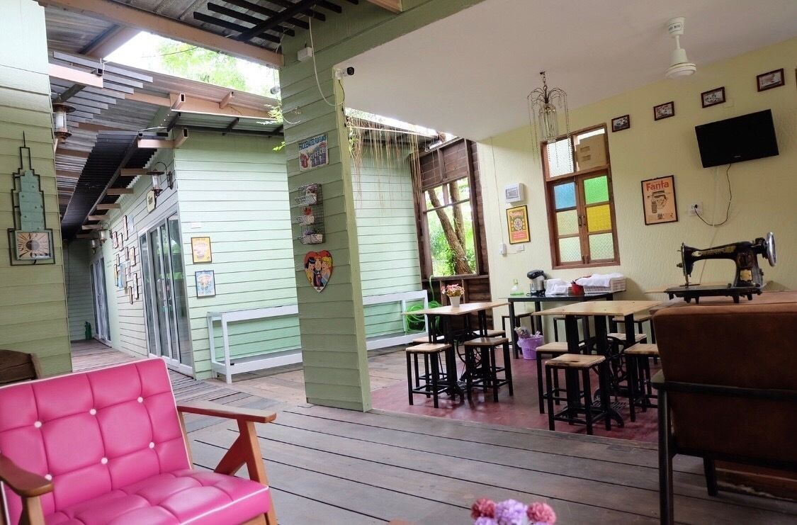 Una habitación acogedora con fachada verde, una mesa de madera con sillas, una máquina de coser y un televisor en la pared.