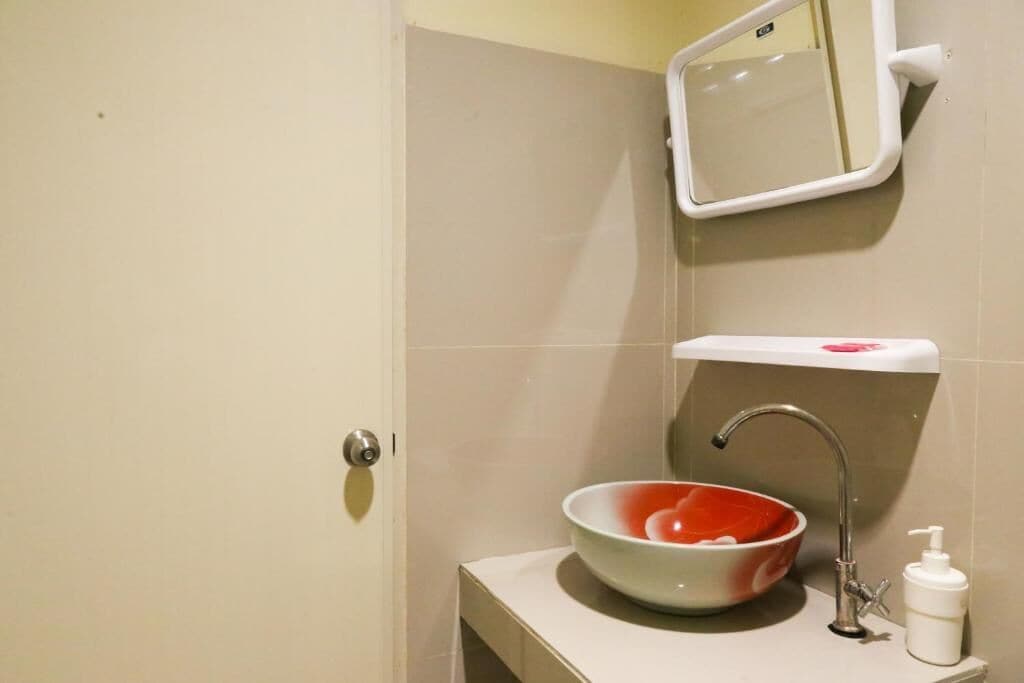 A bathroom with a white sink, a mirror, and a soap dispenser.
