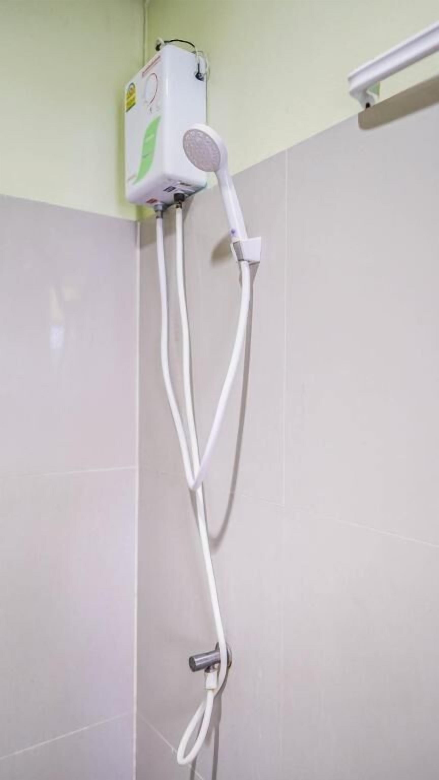 Una ducha con cabezal de ducha manual montado en la pared, conectado a una manguera flexible.