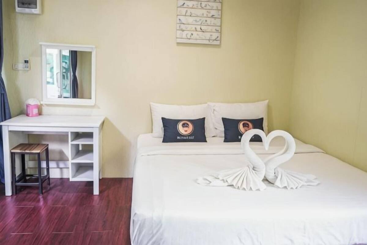 Quarto de hotel com cama, escrivaninha, espelho e uma obra de arte na parede.