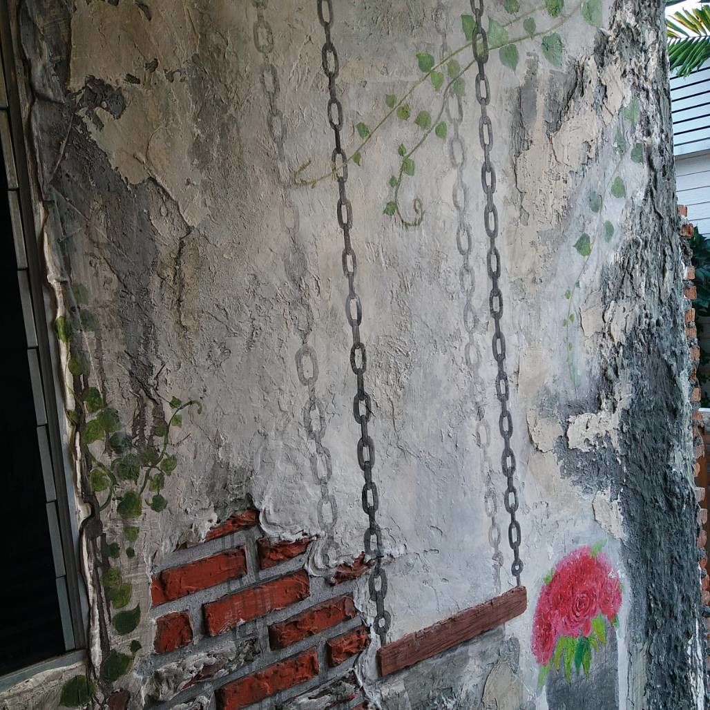 A weathered wall with exposed brickwork and a chain hanging from it.