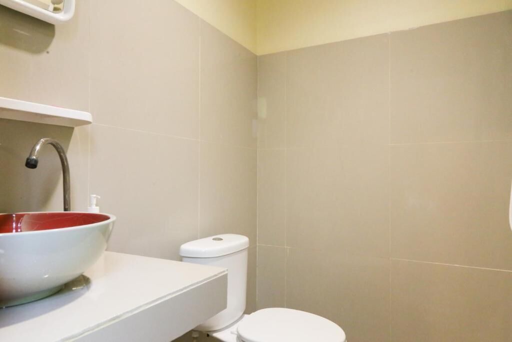 A bathroom with a white sink, red basin, and a white toilet.