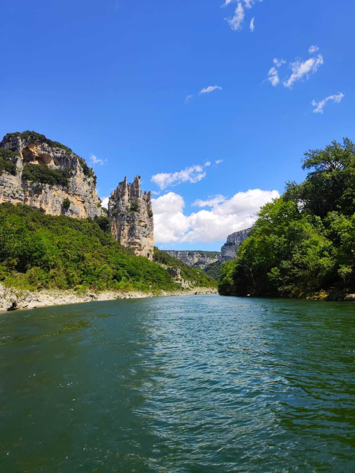 Une rivière bordée de falaises rocheuses et d’une végétation luxuriante de part et d’autre.