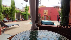 Un patio con piscina, sillas de descanso y una mesa de azulejos.