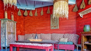 Una habitación con una pared de madera roja, un banco de madera, una mesa con una bandeja y escobas colgadas.
