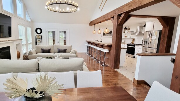 Amplia sala de estar con un sofá grande, una mesa de comedor y una zona de cocina con taburetes de bar.