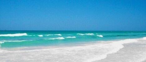 A beach with white sand and turquoise water.