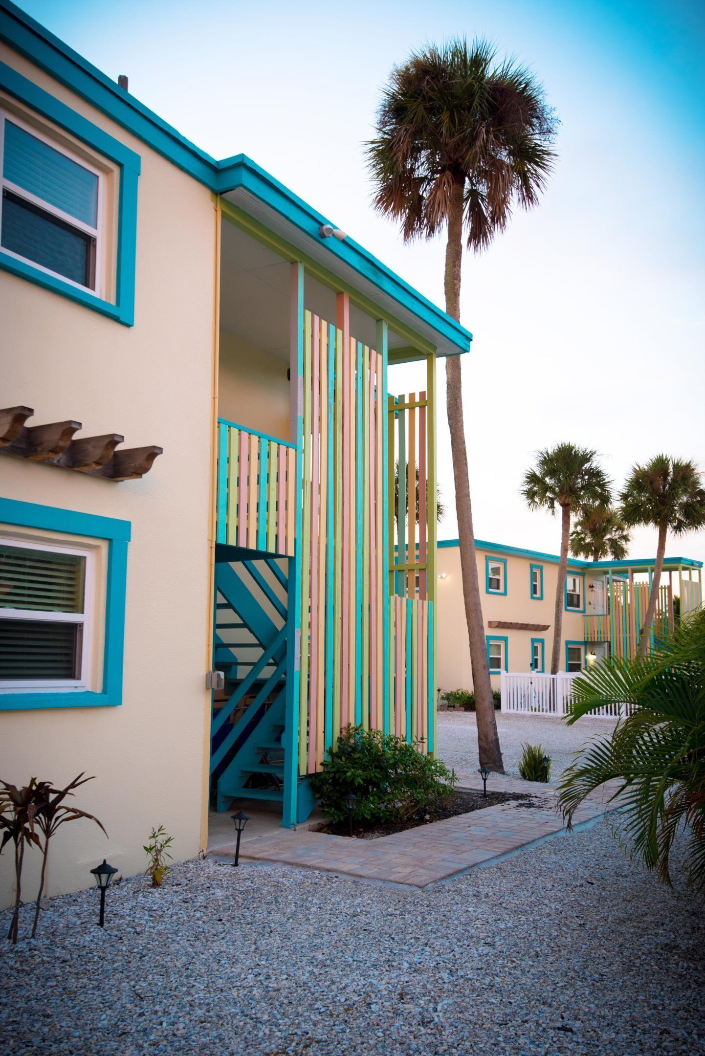 A building with a colorful exterior, a staircase, and palm trees.