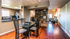 A modern kitchen with a dining area, featuring a glass-top table, black chairs, and a stone accent wall. - On golf course luxurious 2 bed/2 bath condo in the heart of Scottsdale (Scottsdale)