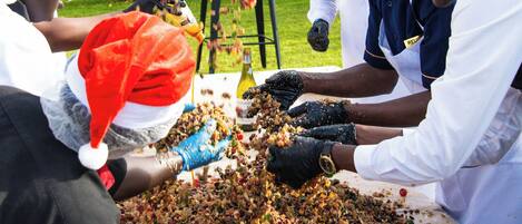 A group of people wearing Santa hats and gloves, preparing food outdoors.
