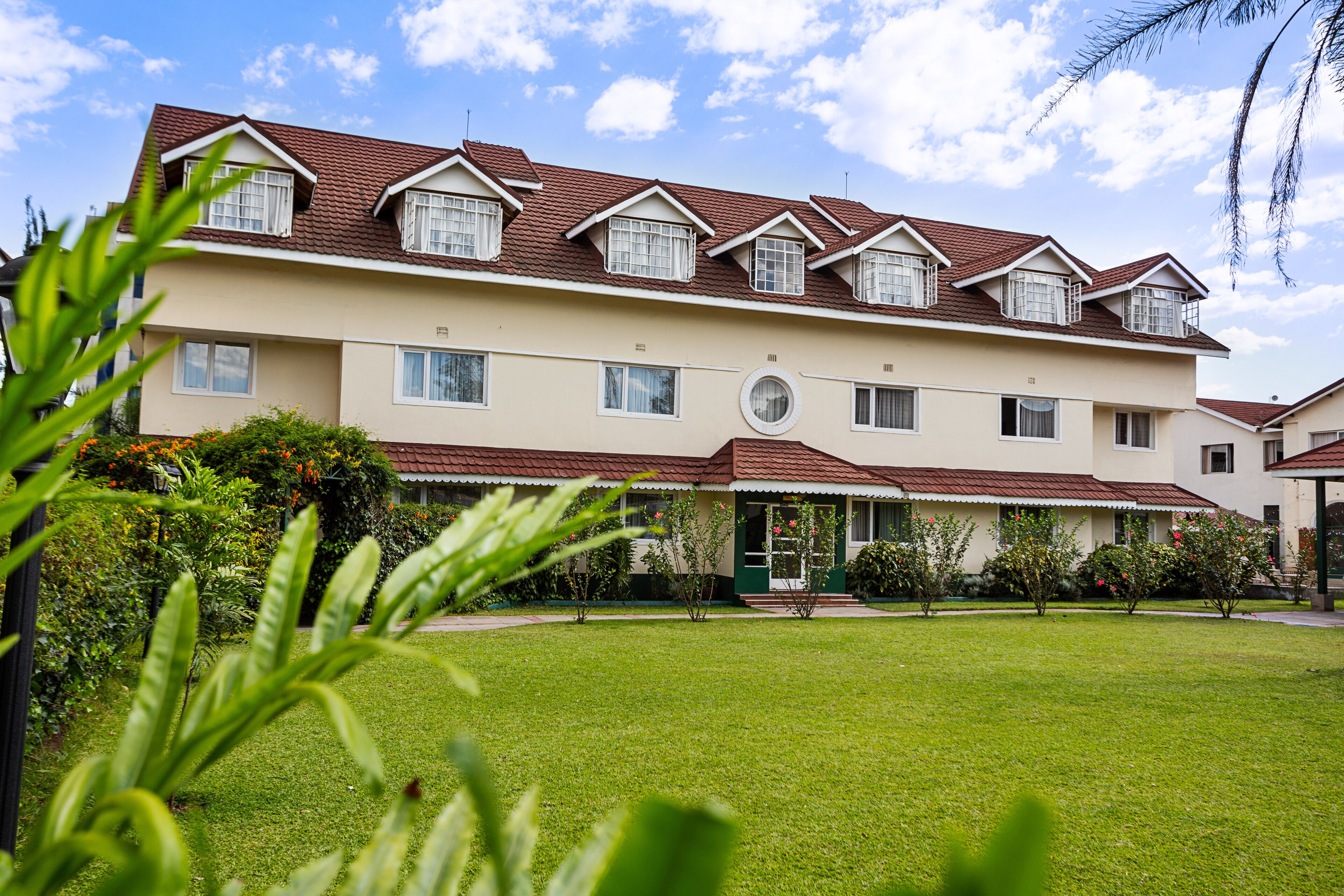 A multi-story building with a symmetrical facade, multiple windows, and a well-maintained lawn.