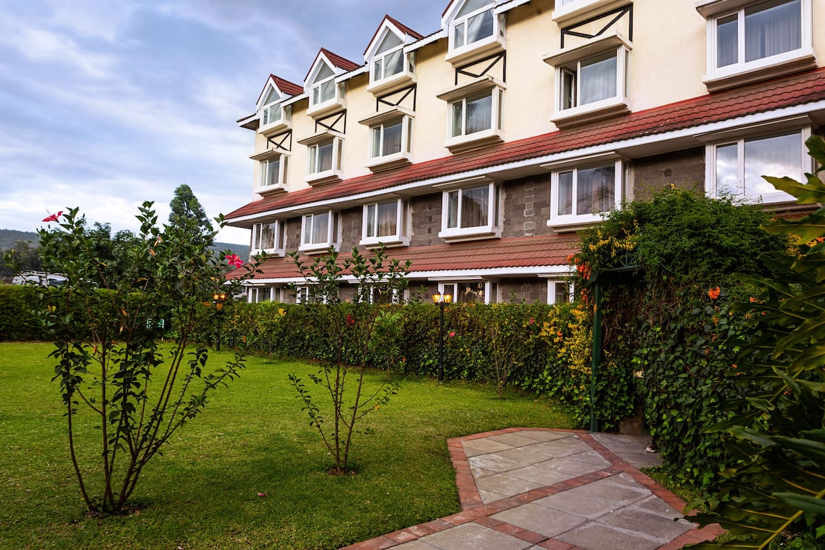 A multi-story hotel with a garden in front.