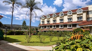 A multi-story hotel with a red-tiled roof, surrounded by well-maintained gardens and palm trees.