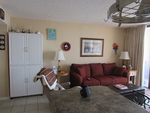Cozy living room with a white cabinet, red sofa, and a small table with a lamp.