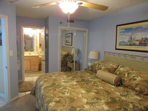 Relax in this serene hotel room with a large bed, framed artwork, and a window overlooking the sea.