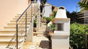 A staircase leading to a building with a stone pathway and a small white structure at the bottom. - Villa Edem (Corfu)