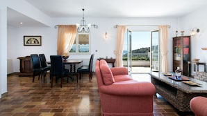 Ein Essbereich mit Tisch und Stühlen, einer Couch und Blick durch eine Glastür.