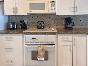 Una cocina equipada con microondas, tostadora, hervidor, cafetera y refrigerador.