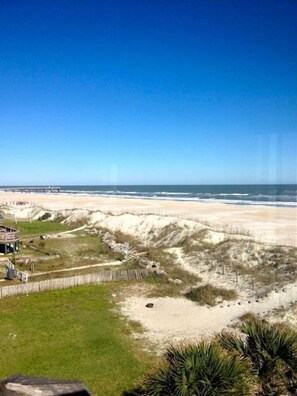 A beach view with a wooden fence, a sandy area, and a structure with a roof. - Surf Side Six C-3 (St Augustine Beach)