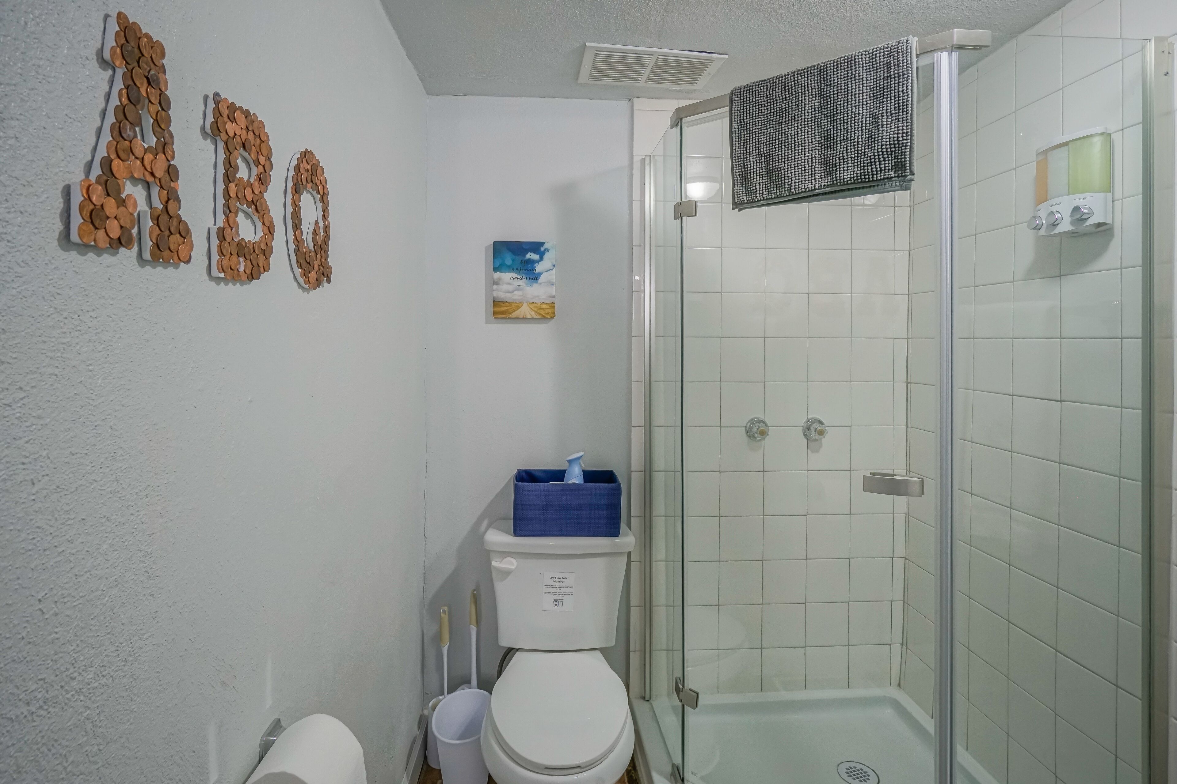 Een badkamer met toilet, douche en decoratieve letters op de muur.