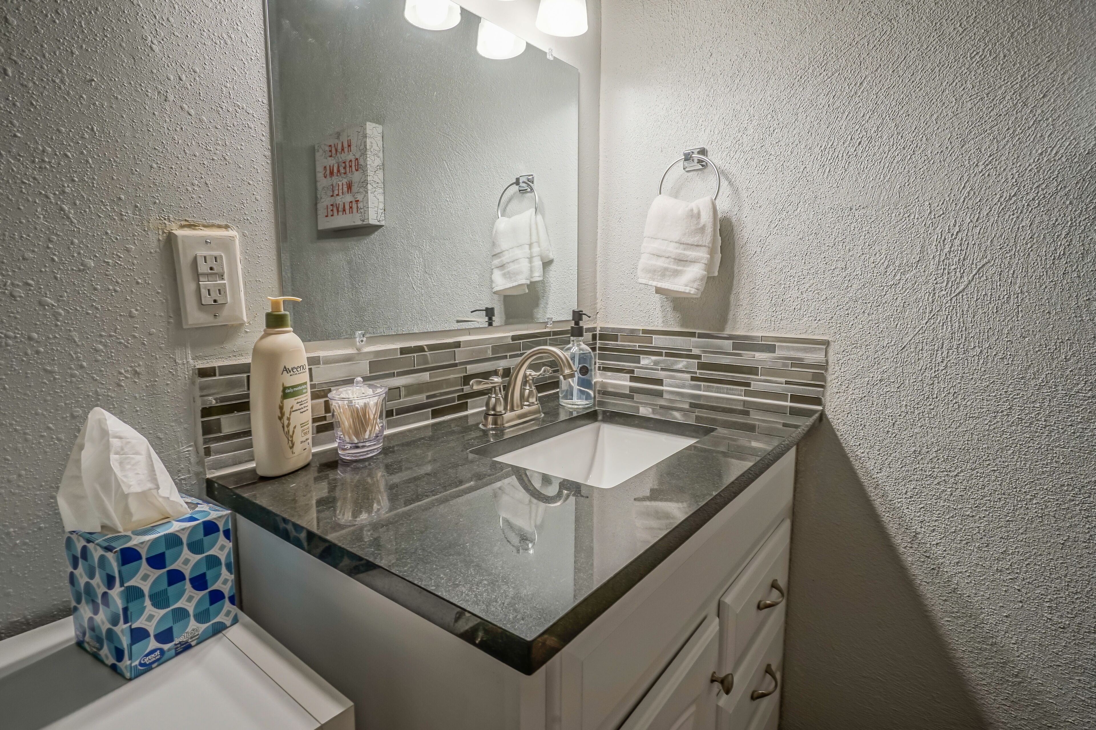 A bathroom with a double sink, a mirror, a towel rack, and a tissue box.