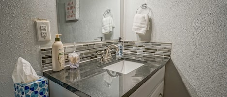A bathroom with a double sink, a mirror, a towel rack, and a tissue box.