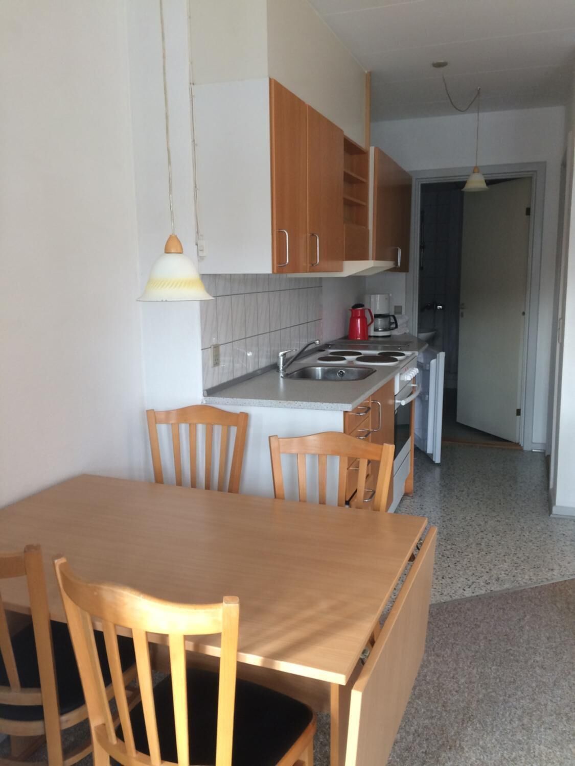 Una cucina compatta con mobili in legno, un lavello, un piano cottura e un'area pranzo con tavolo e sedie.
