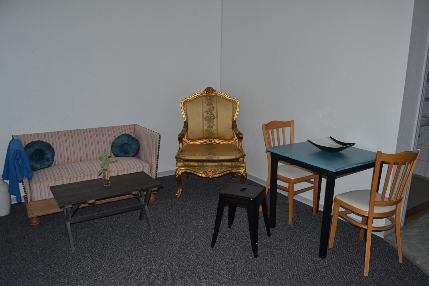 A room with a striped sofa, a small table, a decorative chair, and a dining table with chairs.