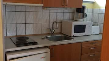 Cocina compacta con refrigerador, microondas, tostadora y cafetera sobre la encimera.