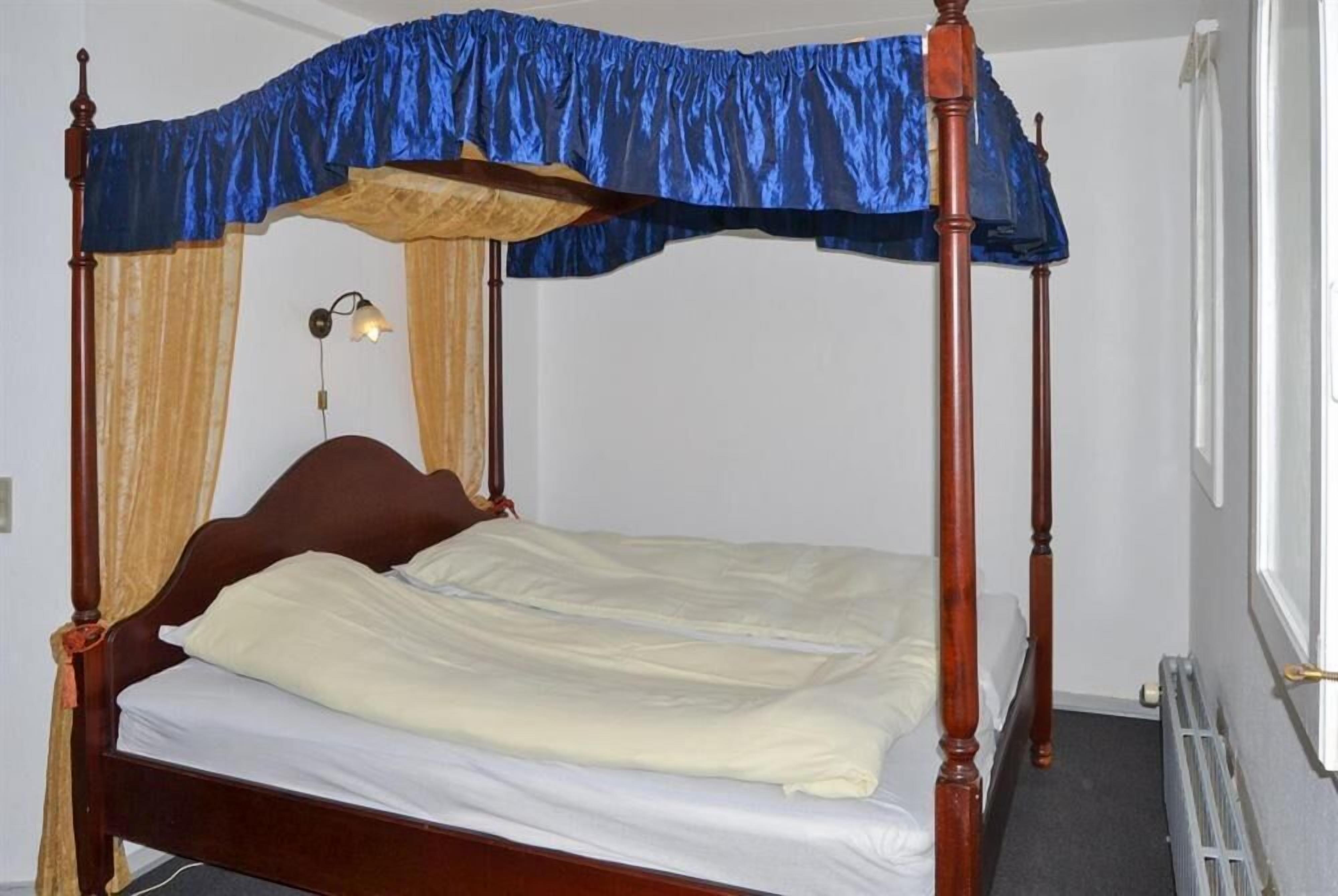 A four-poster bed with a canopy, a bedside lamp, and a radiator.