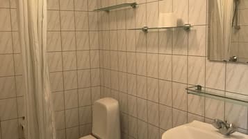 Un bagno con il water, un lavandino e una tenda per la doccia.