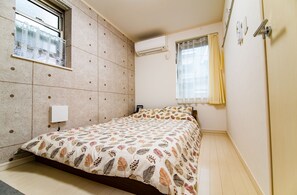 A bedroom with a bed, a window with curtains, an air conditioning unit, and a door. - May Kameido (Tokyo)
