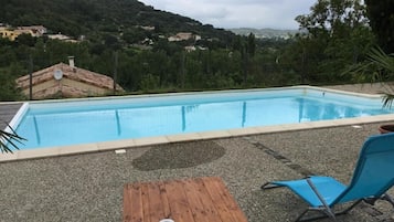 Una piscina al aire libre de temporada, sombrillas