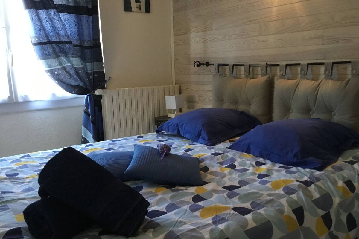 Une chambre d’hôtel avec un lit agrémenté d’une couvre-lit à motifs, de deux oreillers et d’une tête de lit décorative.