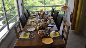 Une table à manger dressée pour le petit-déjeuner, avec vue sur un jardin luxuriant.