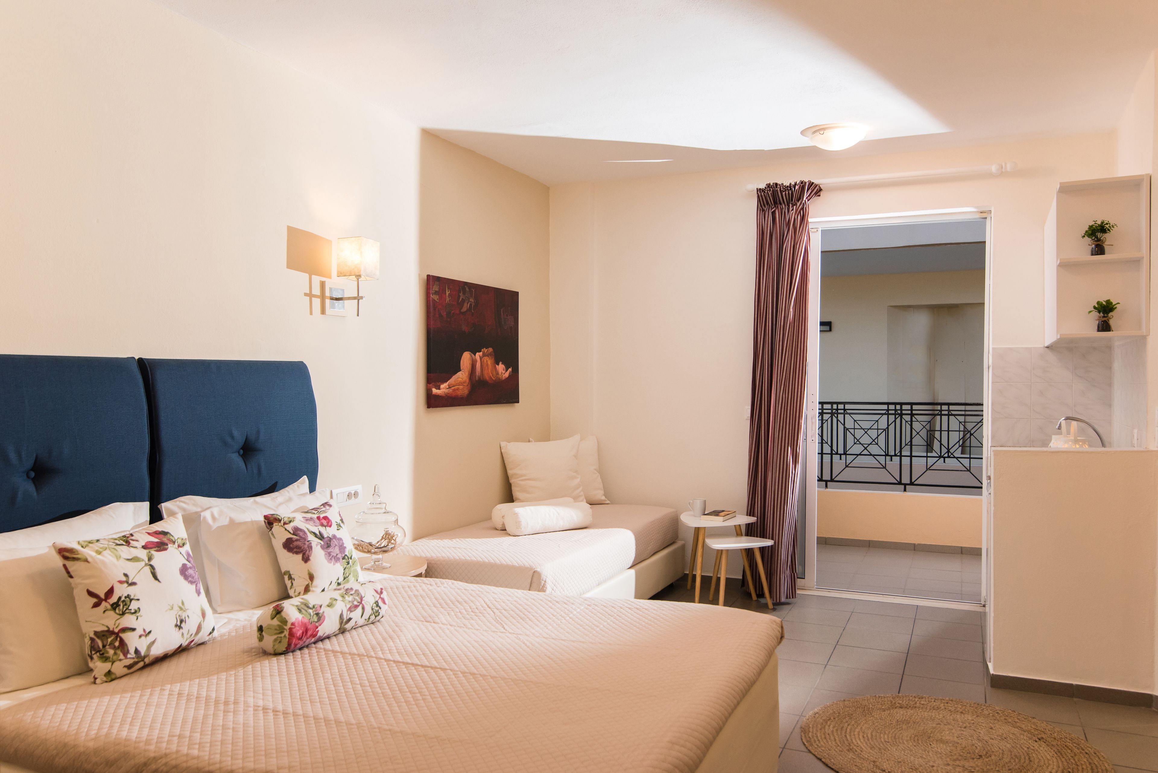 A hotel room with a bed, a sofa, a small table, and a balcony with a railing.