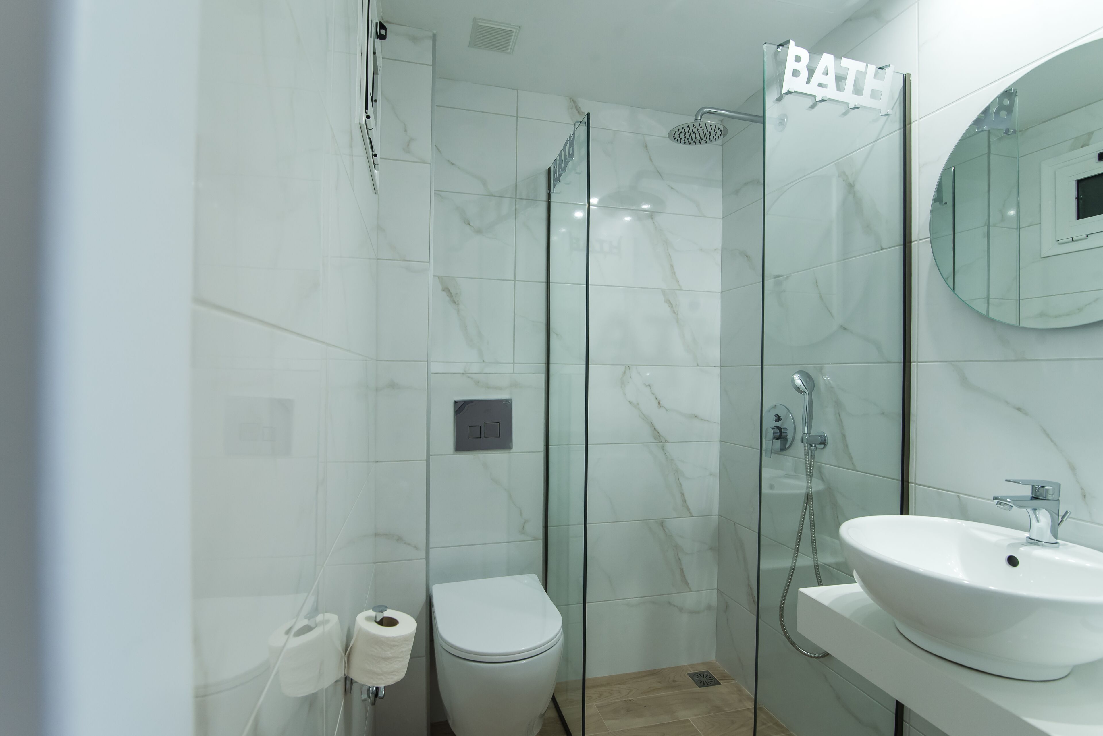 A modern bathroom with a glass shower enclosure, a toilet, and a sink with a mirror.