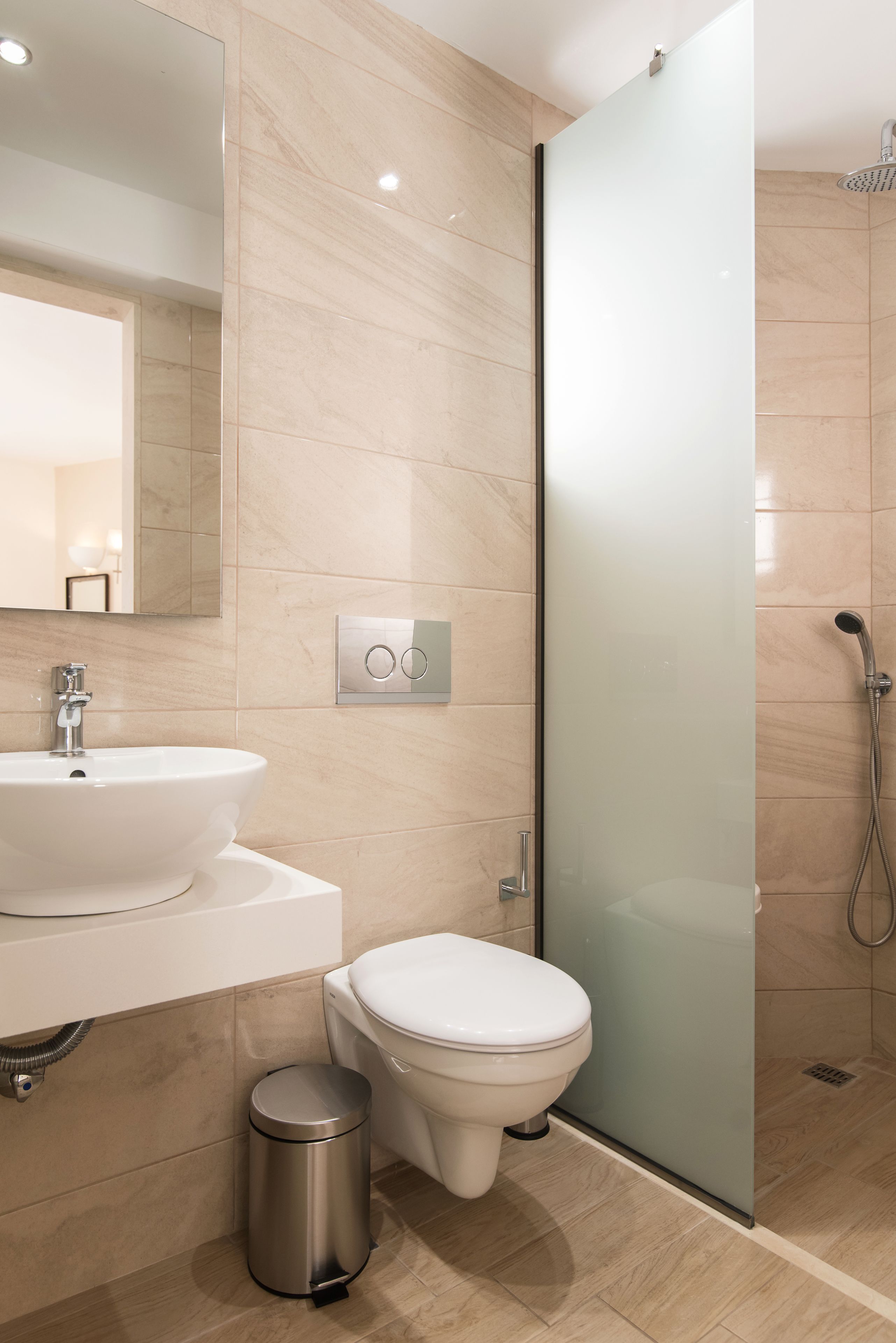 A modern bathroom with a white sink, toilet, and glass shower enclosure.