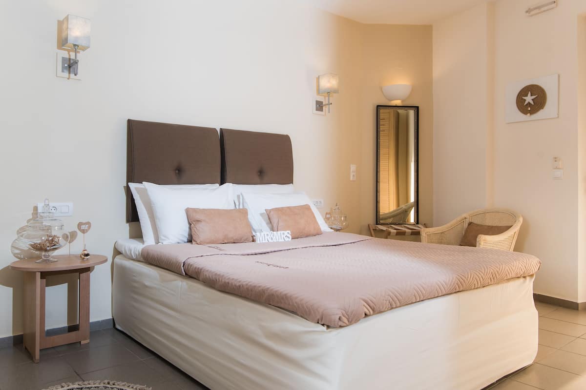 A neatly arranged bedroom with a large bed, bedside tables, a mirror, and a chair.