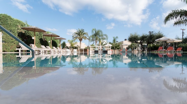 Una piscina al aire libre de temporada, sombrillas