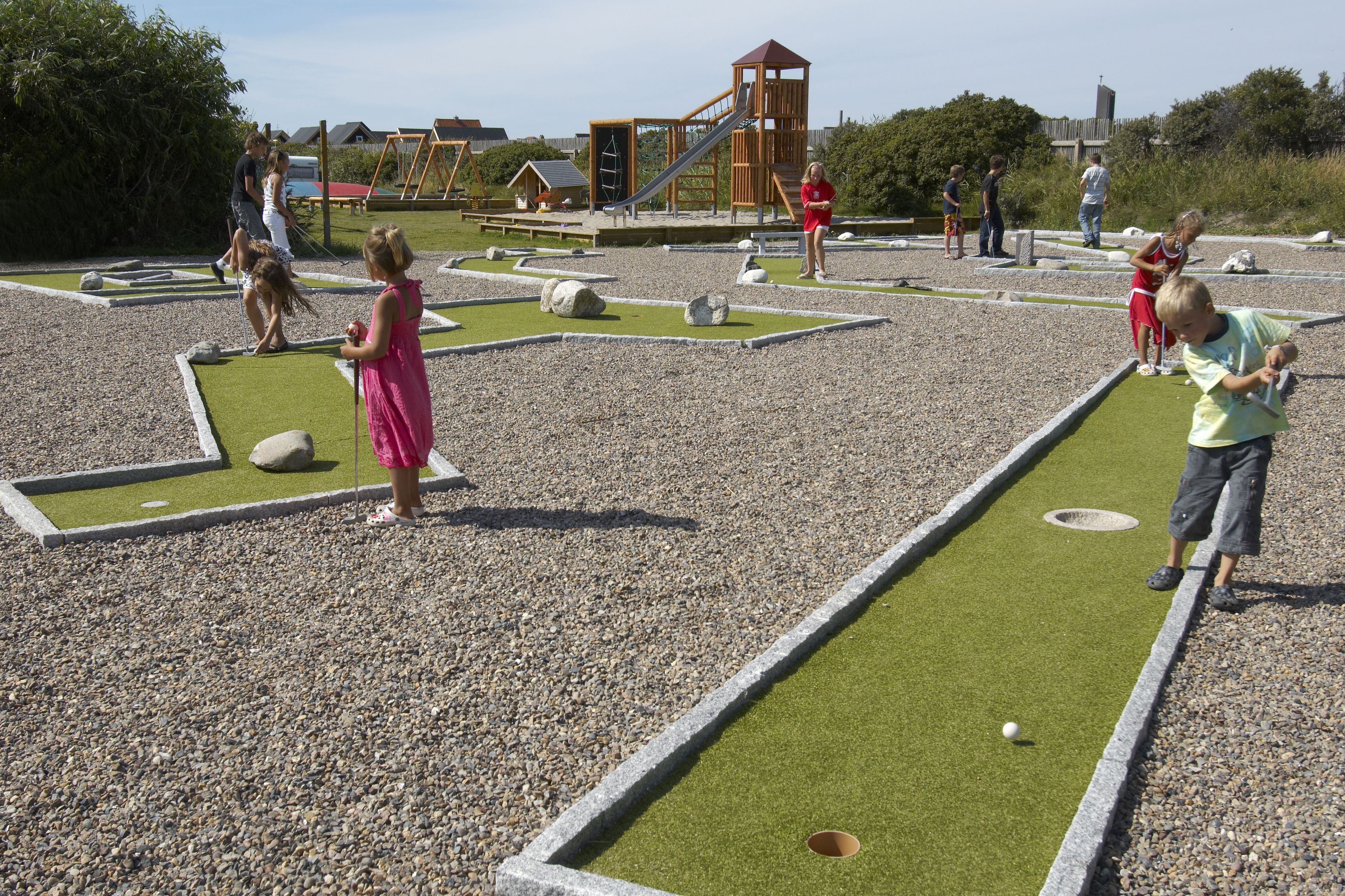 A children's play area with a slide, swings, and a small building structure.