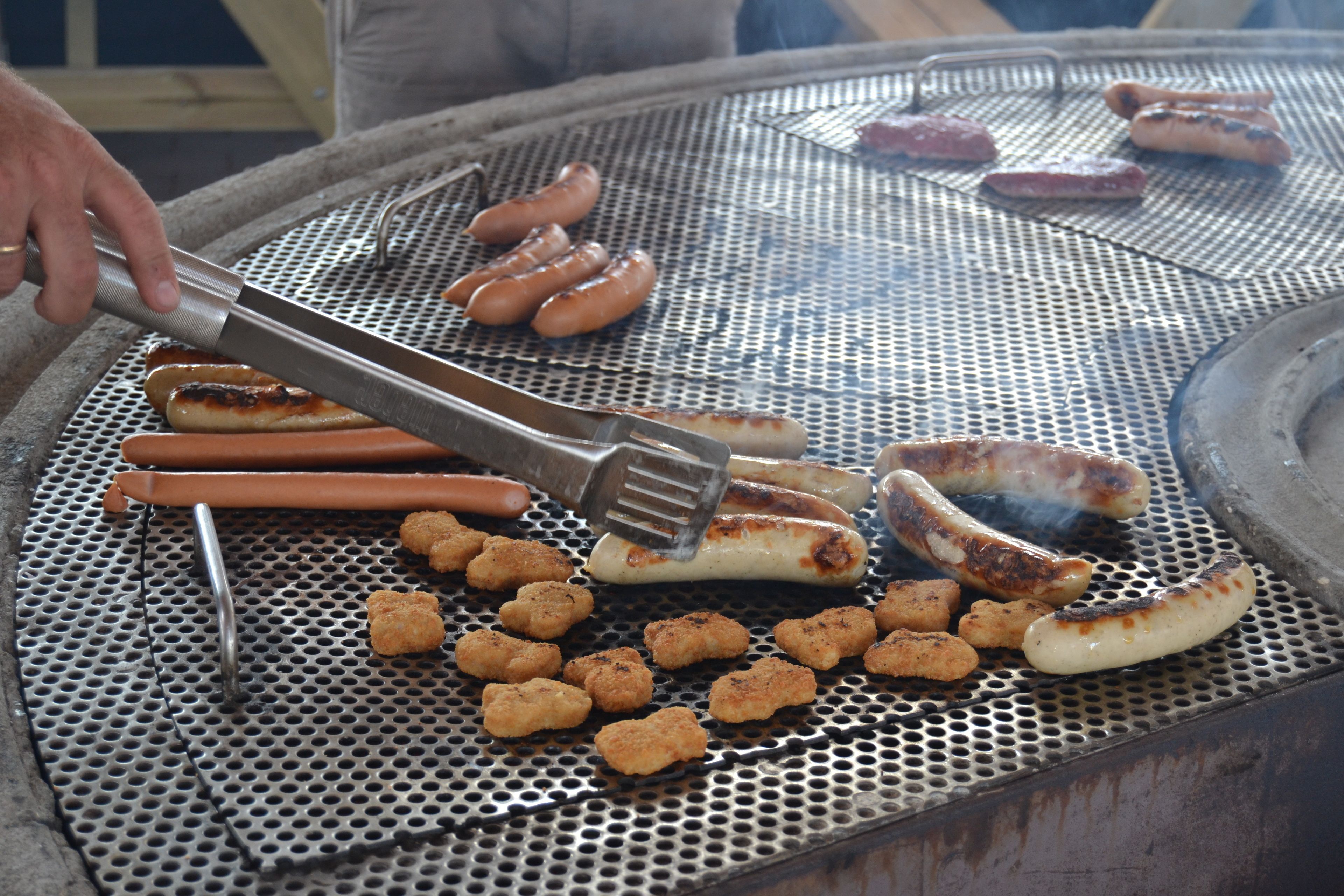 Una griglia con salsicce e tater tots in cottura.