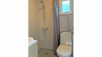 Une petite salle de bain avec douche, toilettes et lavabo.