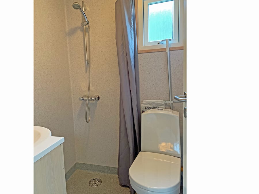 Un baño pequeño con ducha, inodoro y lavamanos.