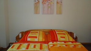 A bedroom with a bed, a nightstand, and three wall-mounted paintings of flowers. - Pension Thaler Hof (Thale)